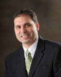 A man in suit and tie smiling for the camera.